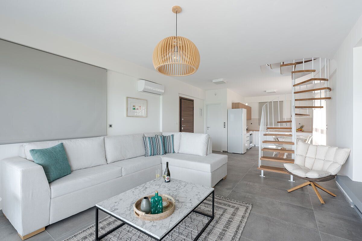 Een moderne woonkamer met een witte bank, een salontafel en een bijzondere spiraaltrap.