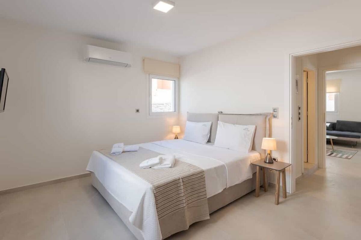 Una habitación de hotel moderna con una cama grande, lámparas de noche y una mesita.