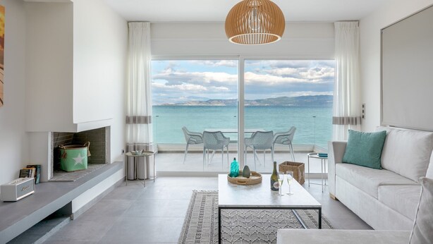 Een moderne woonkamer met een bank, salontafel en uitzicht op zee door grote ramen.