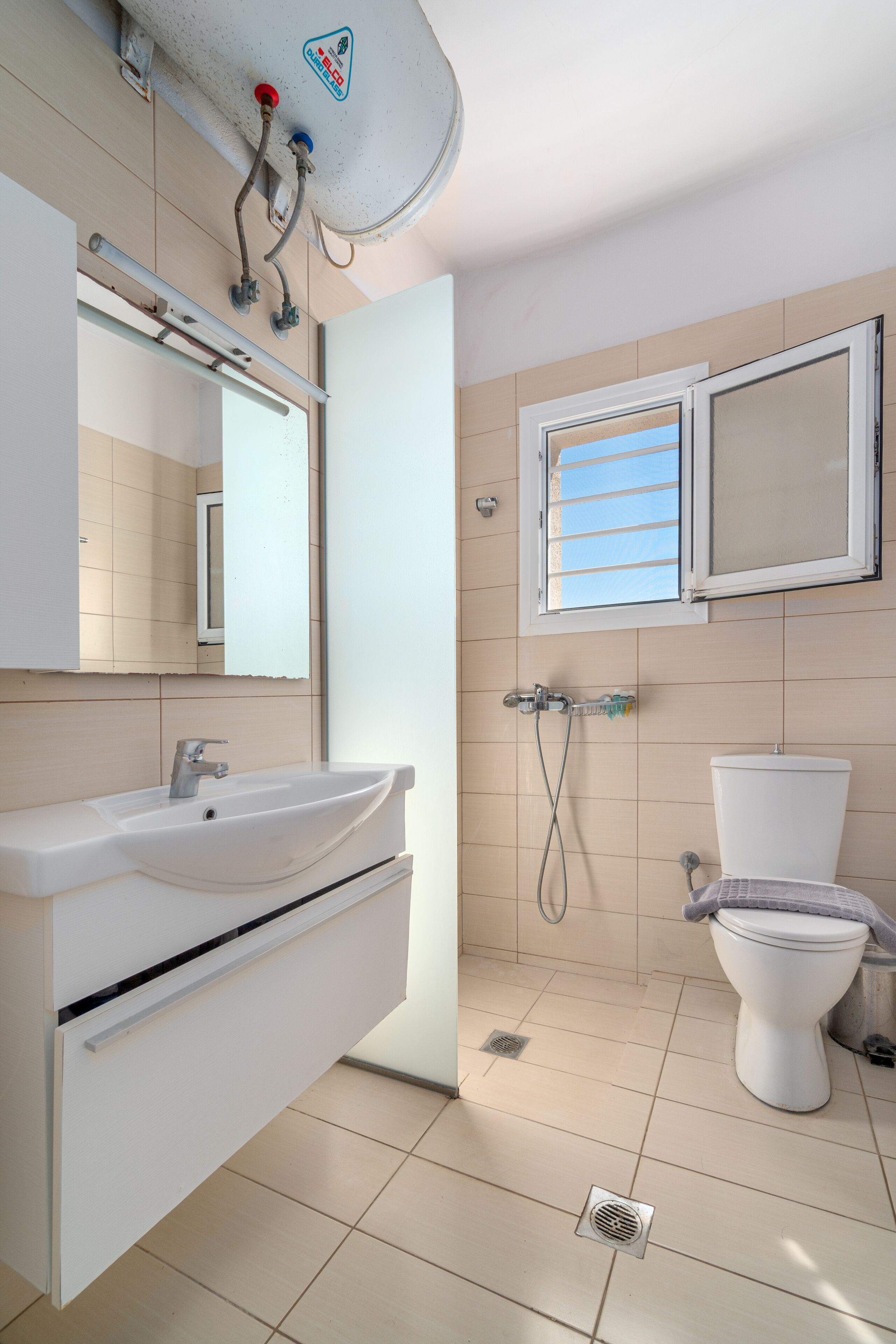 Une salle de bain avec un lavabo blanc, un miroir et des toilettes.