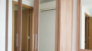 Una habitación con un armario de madera, un espejo y suelo de baldosas.