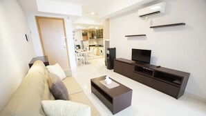 Una sala de estar moderna con sofá, mesa de centro, televisor y mueble de entretenimiento.