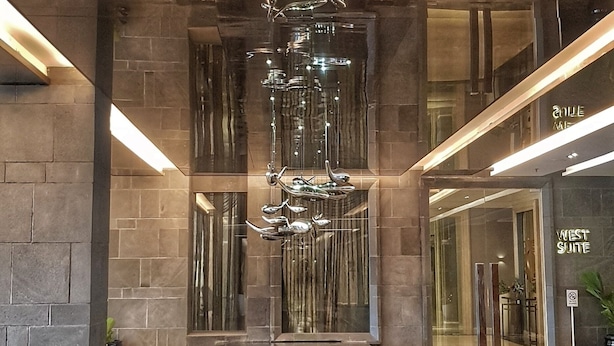 A modern lobby with a reflective water feature, a security camera, and a sign for 'West Suite'. - Apatel Roseville SOHO & Suite (South Tangerang)