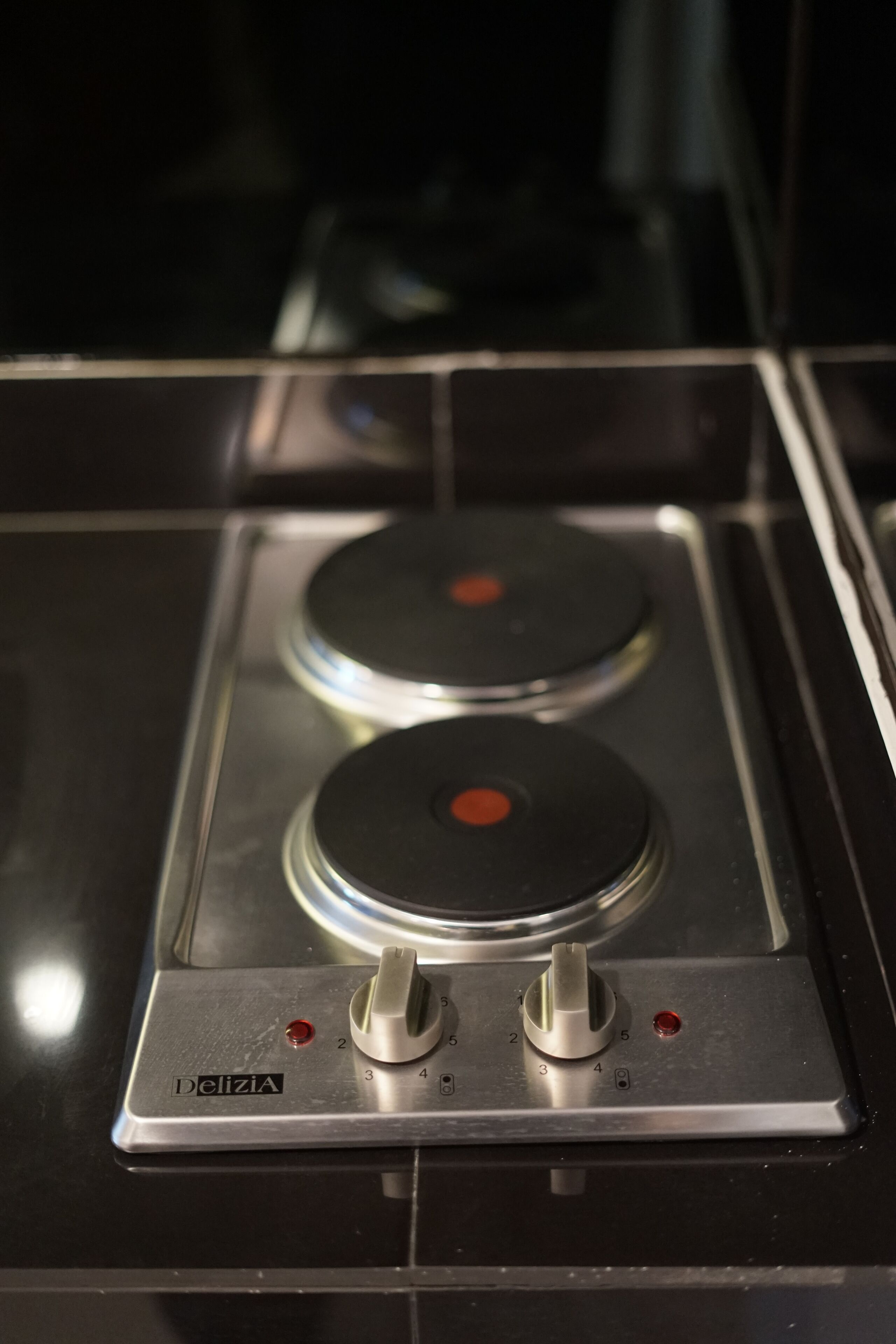 Une cuisinière de la marque Delizia, dotée de deux brûleurs et de boutons de commande.
