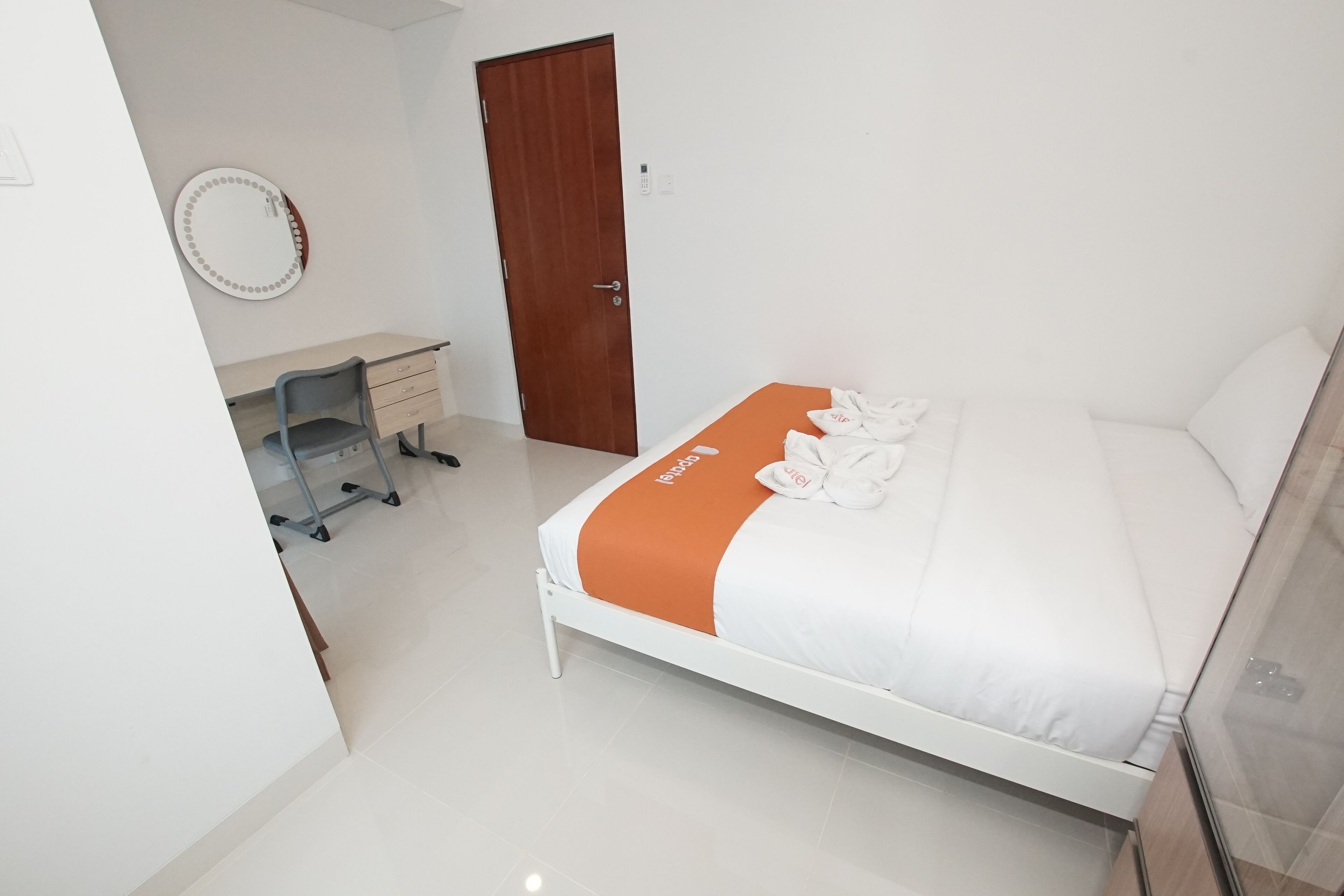 A hotel room with a bed, a desk, a chair, a wardrobe, and a door.