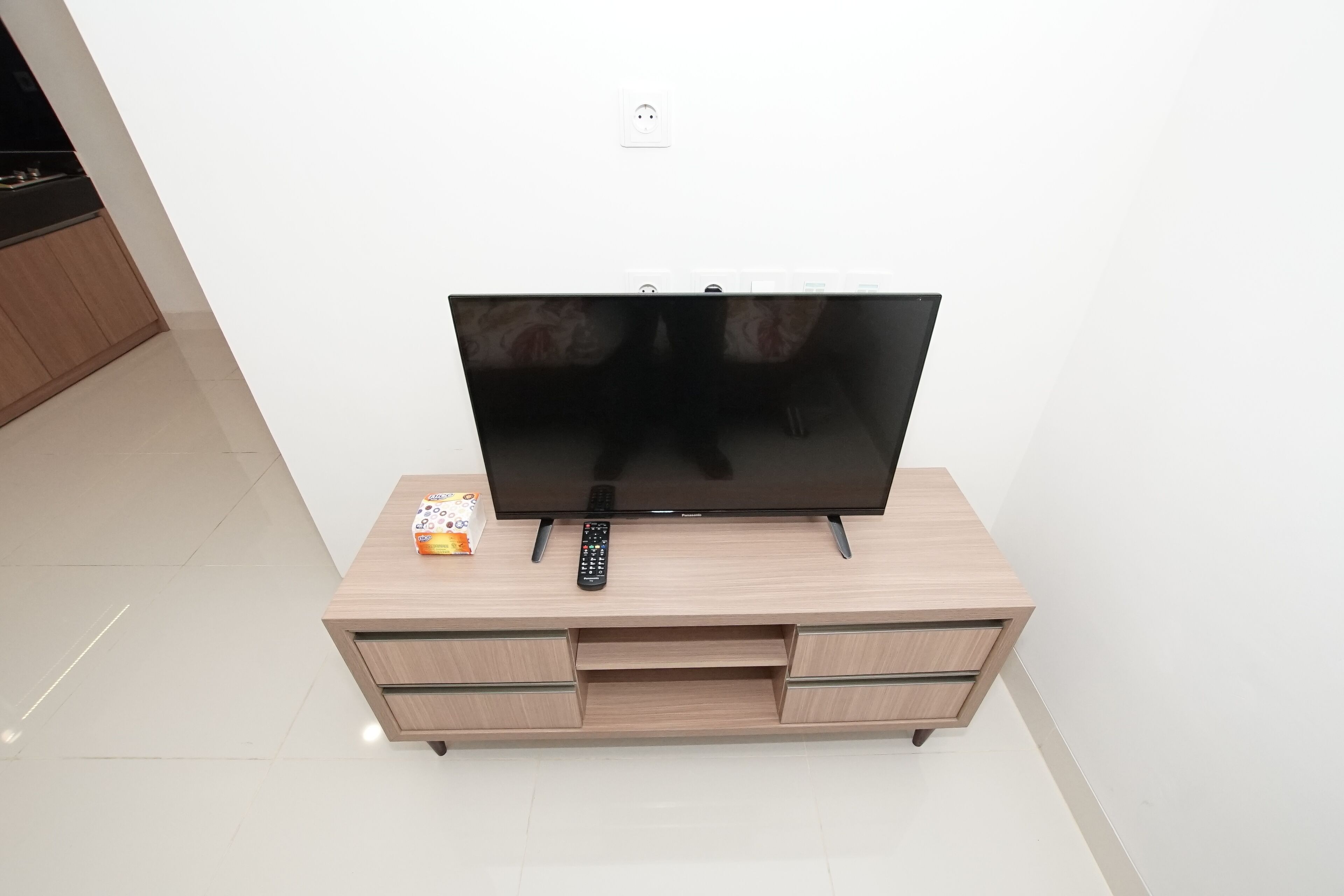 Televisor de pantalla plana sobre un mueble bajo de madera con cajones.