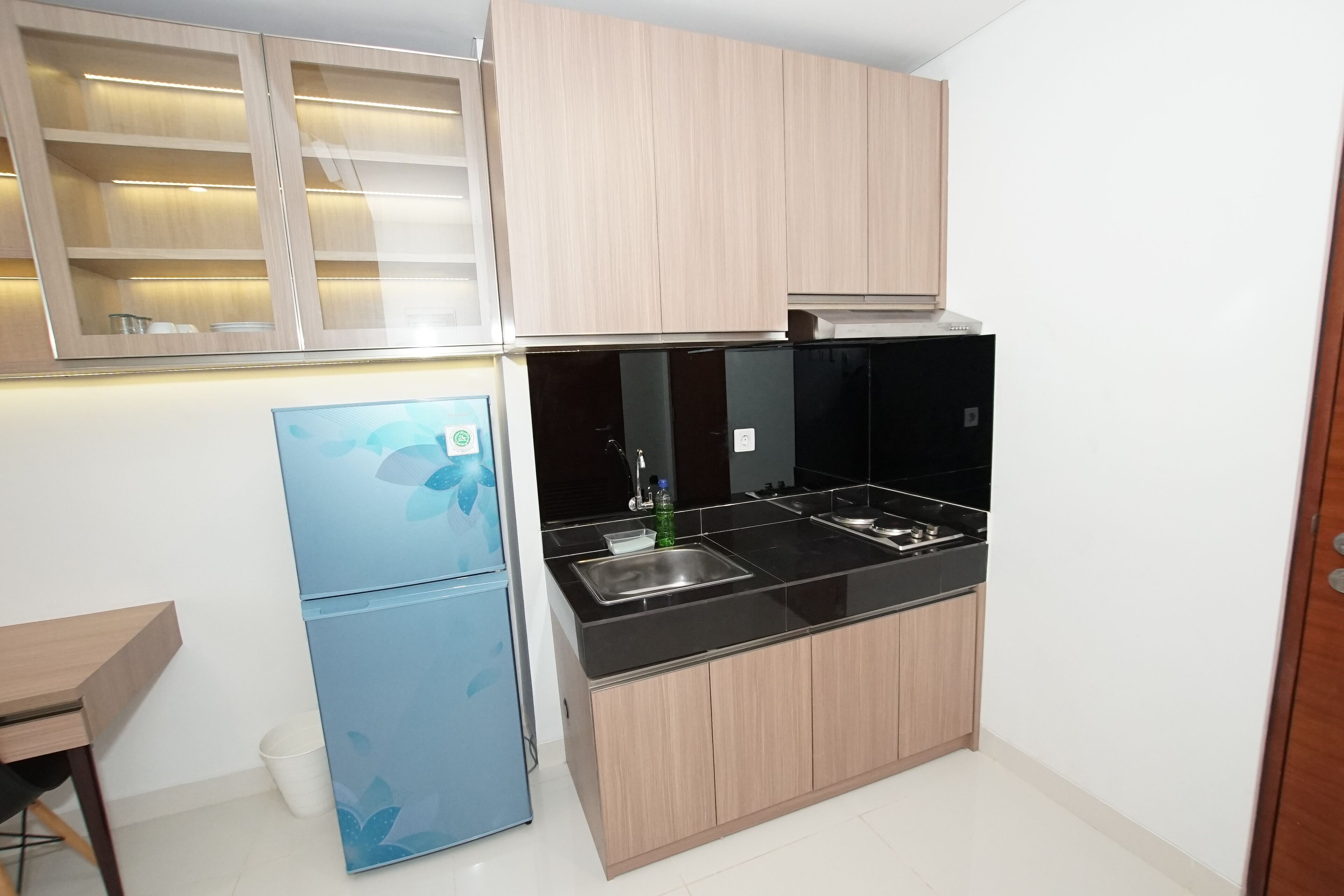 A compact kitchen with a refrigerator, stove, and wooden cabinets.