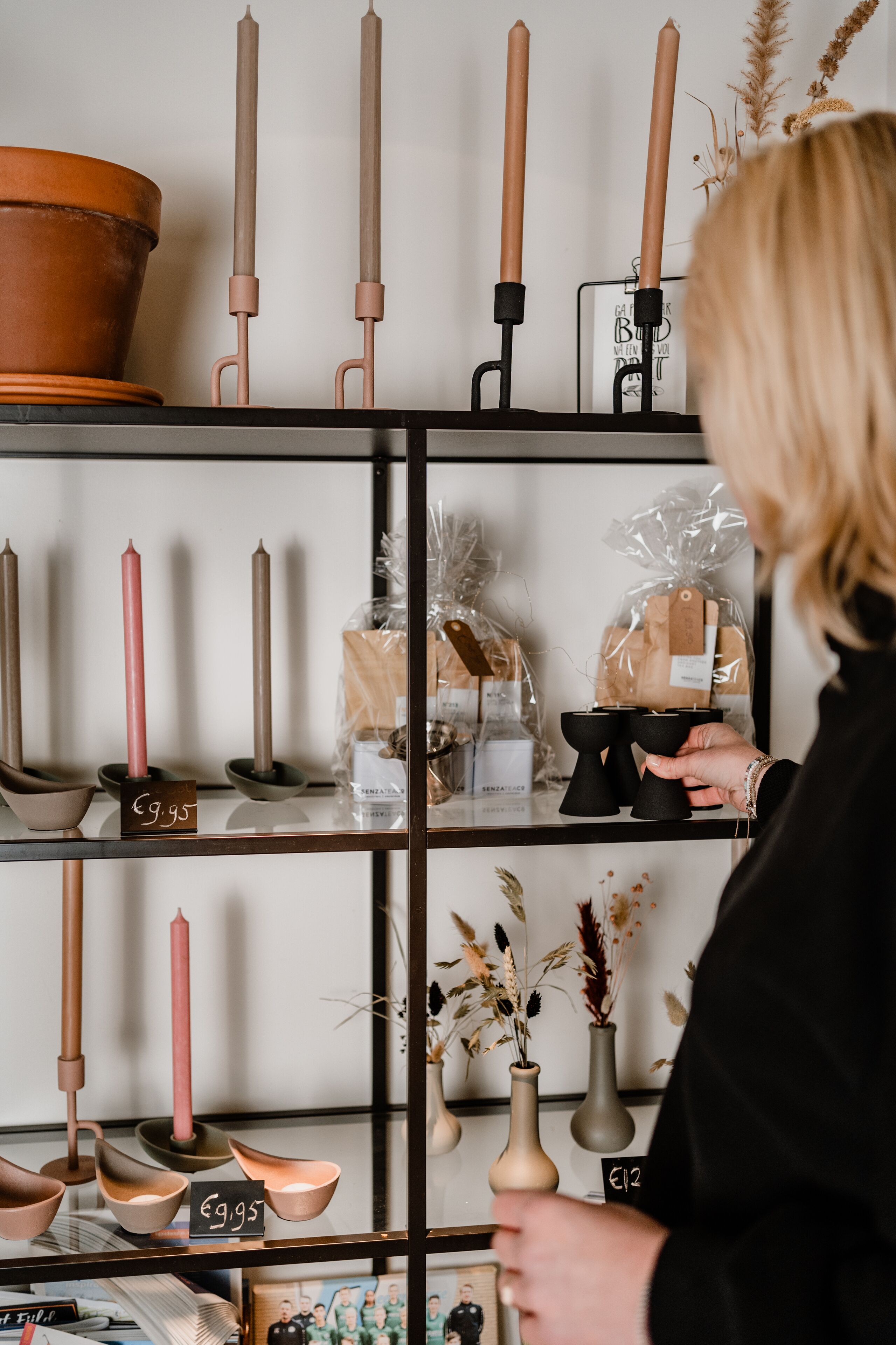 A woman browsing shelves with candles and bowls.