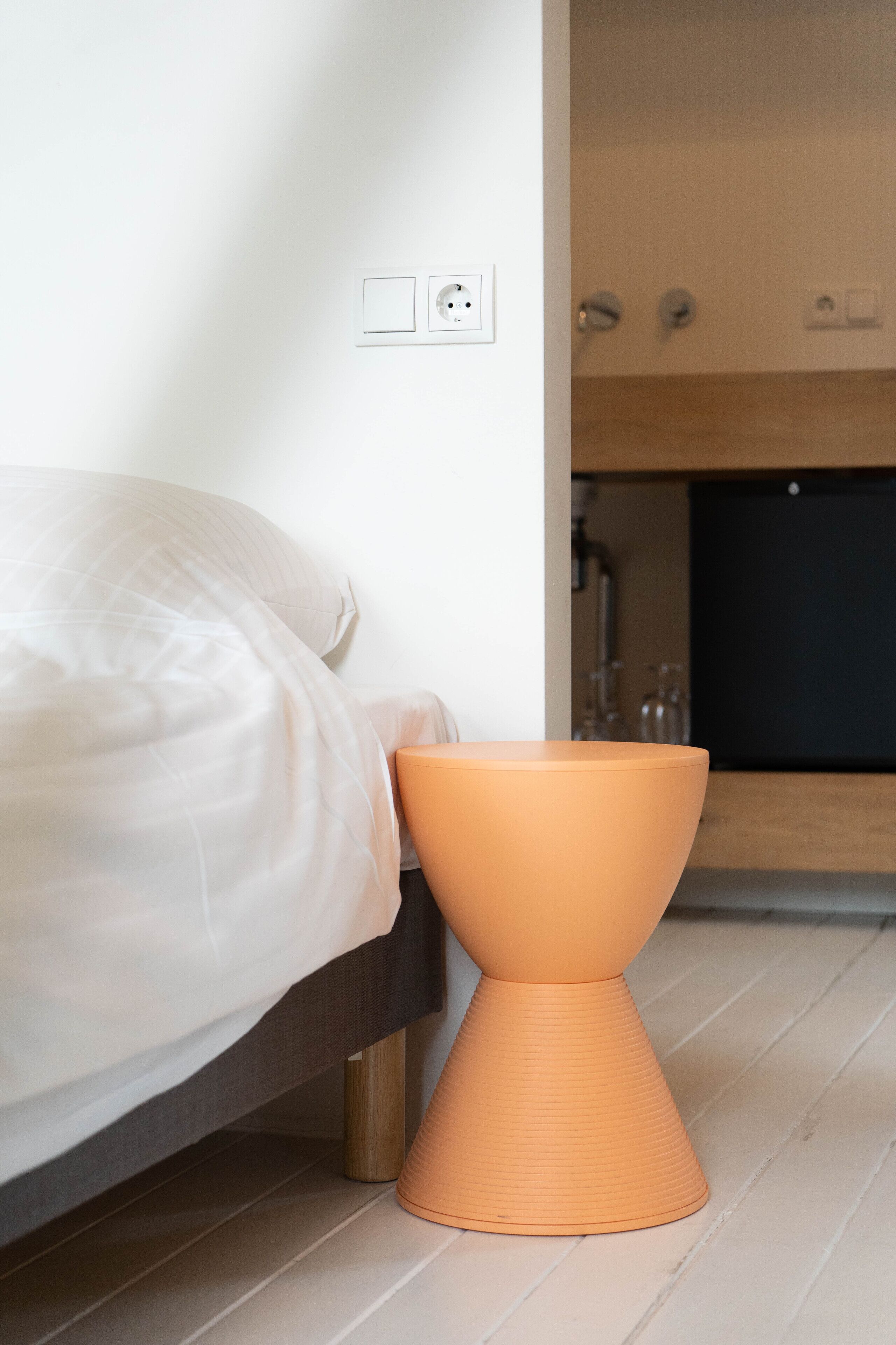 Un dormitorio con cama, una mesita de noche y un enchufe.