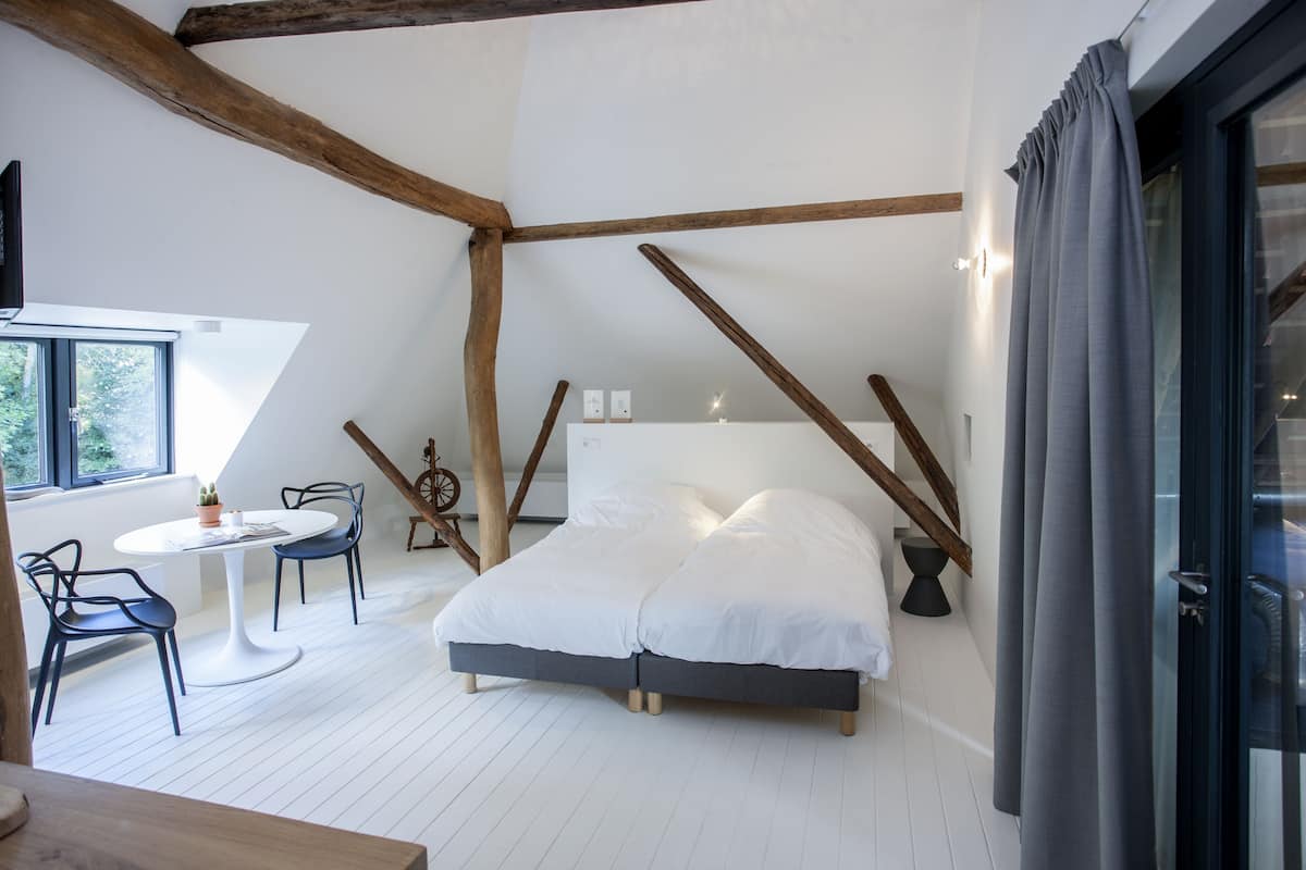 A bedroom with a bed, a small table with chairs, and a window.