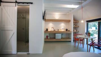 A modern kitchen with wooden shelves, a dining area with red chairs, and a large window with a view.