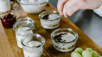 Une table en bois sur laquelle sont posés des bocaux contenant différents aliments, notamment un bol de yaourt et un bocal de noix.