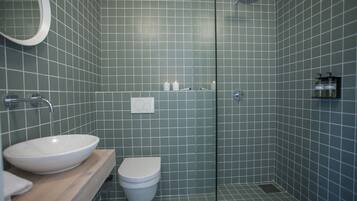 Un baño moderno con lavamanos grande, inodoro y cabina de ducha de vidrio.