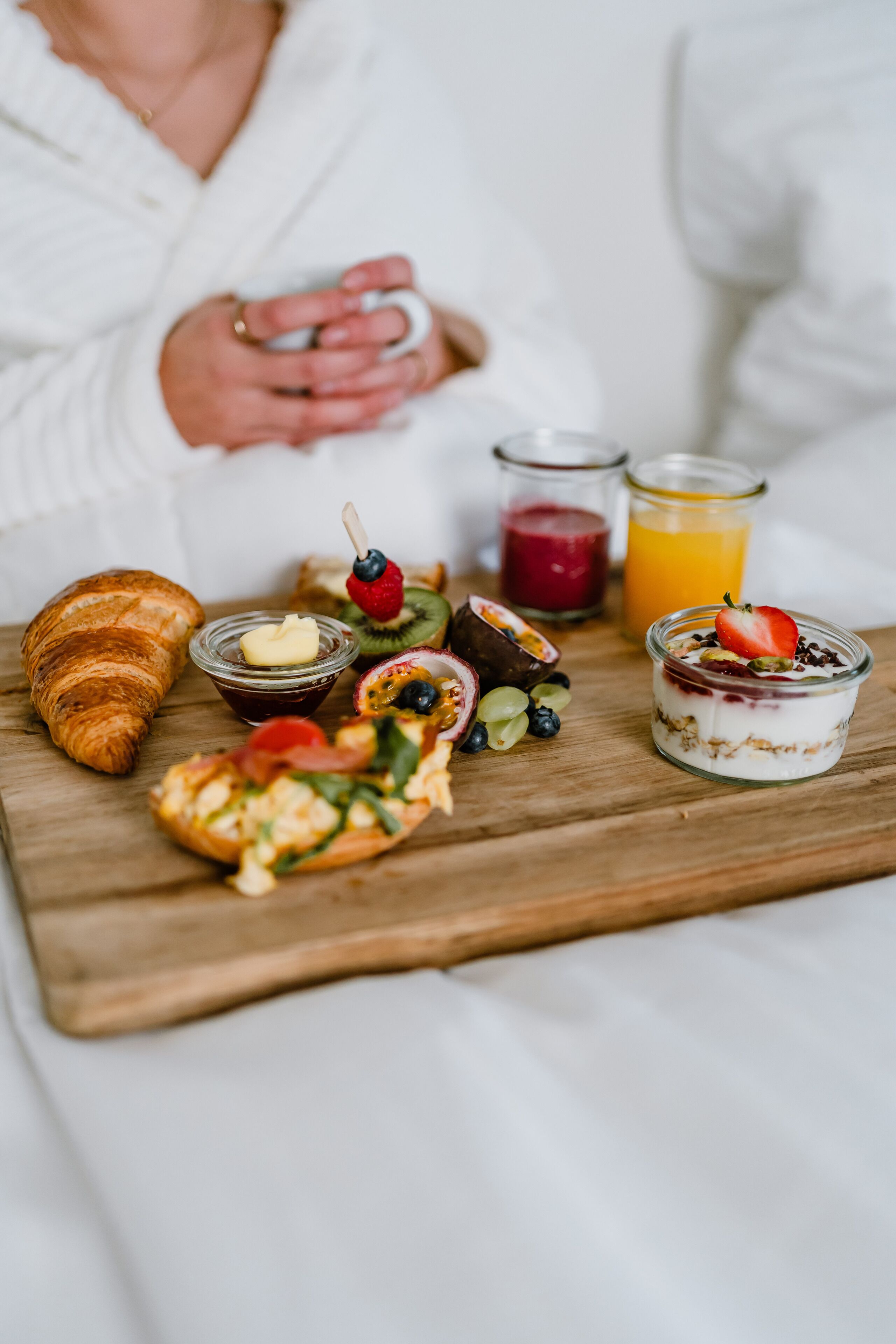 Een ontbijtplateau met croissants, fruit en een yoghurt parfait.