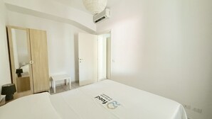 Ein Hotelzimmer mit einem Bett, einem Holzschrank, einer Bank und einer Tür zu einem anderen Raum.