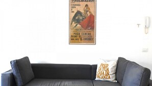 Ein schwarzes Ledersofa mit Kissen, einem Wandtelefon und einem Poster.