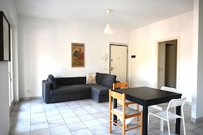Ein Zimmer mit einer Couch, einem Esstisch und Stühlen.