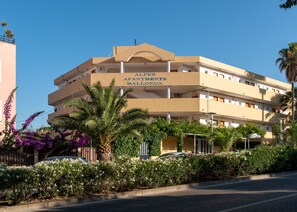 Un immeuble à plusieurs étages doté de balcons, entouré d’une végétation luxuriante et de plantes en fleurs.
