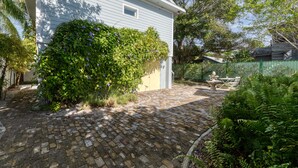 A house with a brick patio, a covered outdoor seating area, and a lush green hedge. - Lido Beach Walk! One block to beach! (Sarasota)