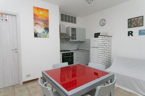 A compact kitchen with white cabinets, a gas stove, and a refrigerator.