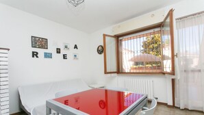 A room with a bed, a table with a red top, a window with bars, and a wall with letters spelling 'REARE'.