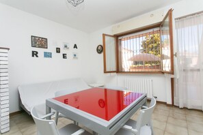 A room with a bed, a table with a red top, a window with bars, and a wall with letters spelling 'REARE'.