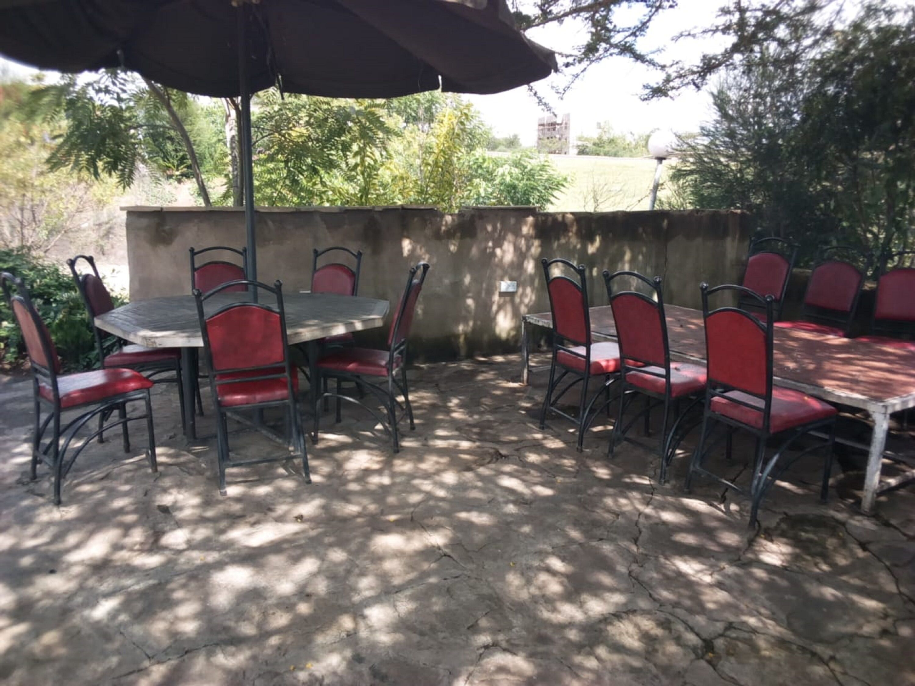 Un patio al aire libre con una mesa y sillas, piso de concreto y una pared de fondo.