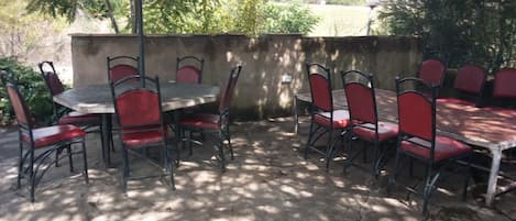 Un patio al aire libre con una mesa y sillas, piso de concreto y una pared de fondo.