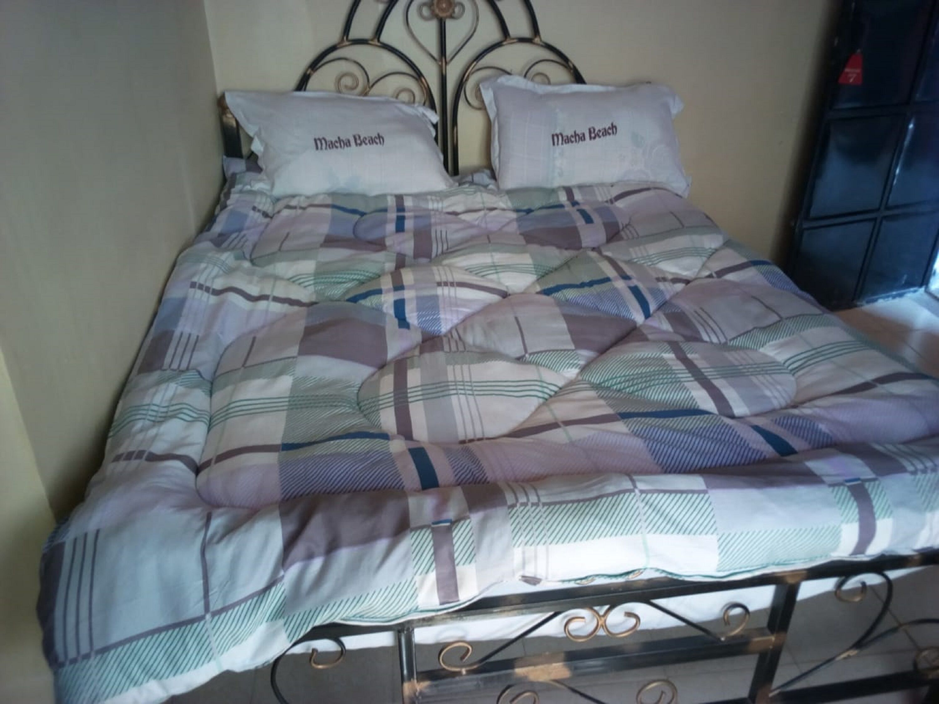 A bed with a plaid bedspread and two pillows labeled "Macha Beach".