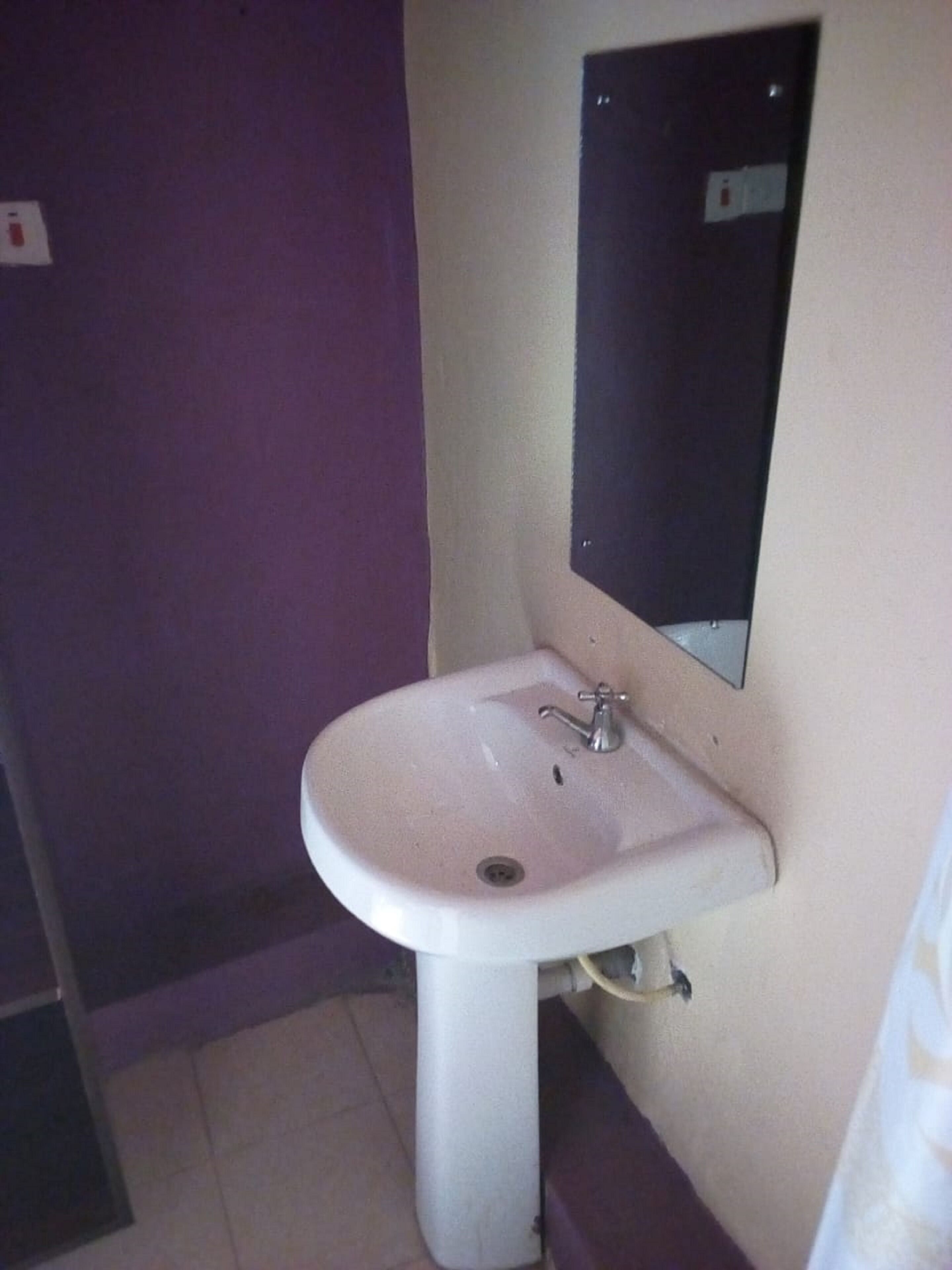 A bathroom with a white sink, a mirror, and purple walls.
