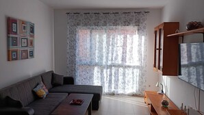 Una sala de estar con sofá, mesa de centro, televisor y aparador.
