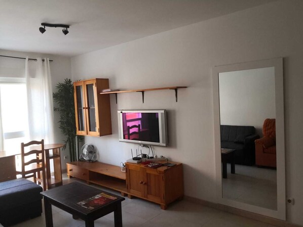 A living room with a TV, wooden cabinet, and a sofa.