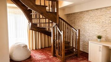A wooden staircase with a stone wall, a bean bag, and a cabinet.