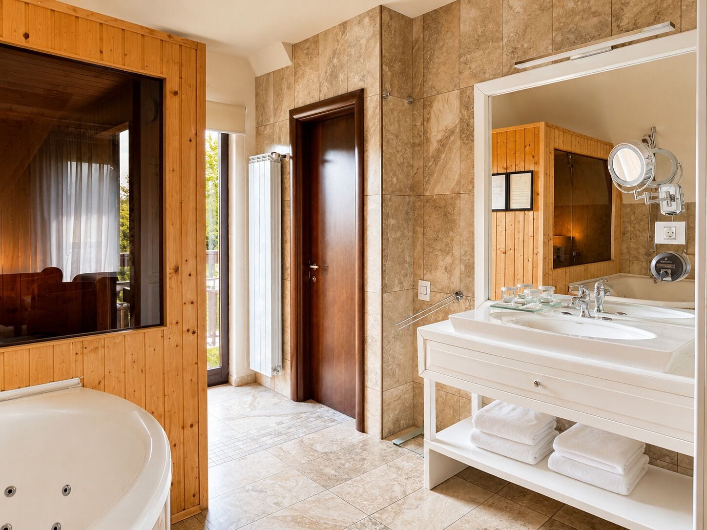 Un baño moderno con una bañera grande, un lavabo doble y un espejo amplio.