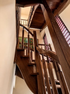 Eine Wendeltreppe mit hölzernen Geländern und Blick auf ein Bild an der Wand.