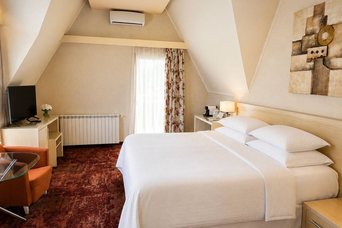 Ein Hotelzimmer mit Bett, Schreibtisch mit Stuhl, Fernseher und Heizkörper.