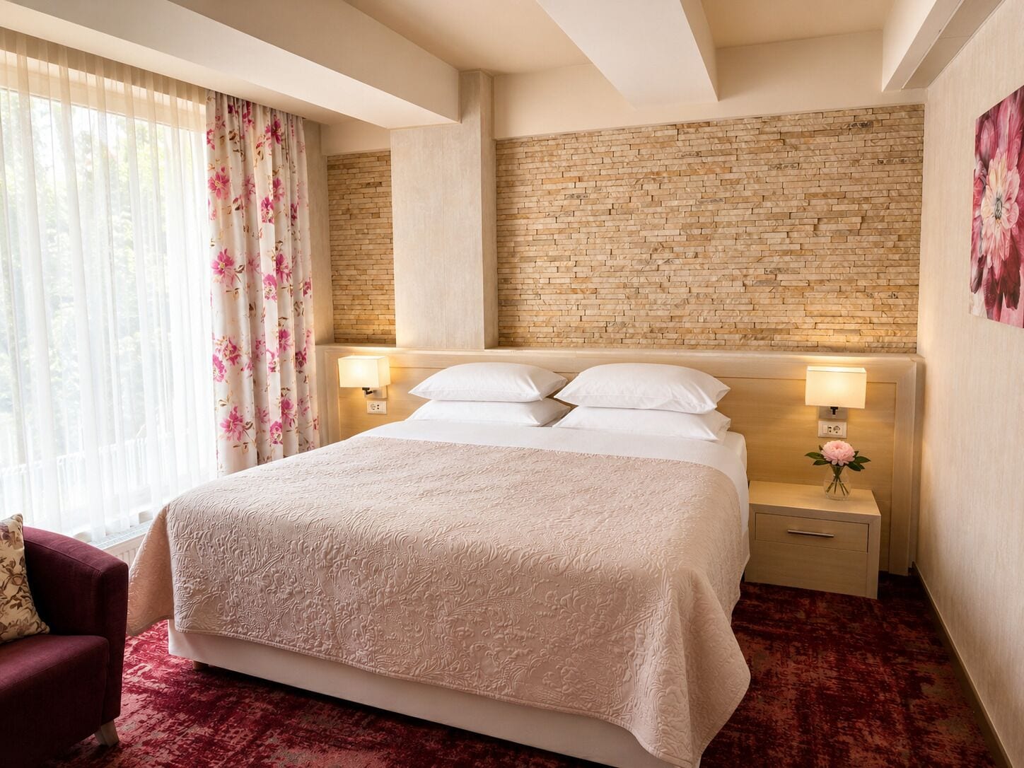 Quarto de hotel com cabeceira de tijolos, uma cama grande com roupa de cama branca, um tapete vermelho e duas luminárias de cabeceira.