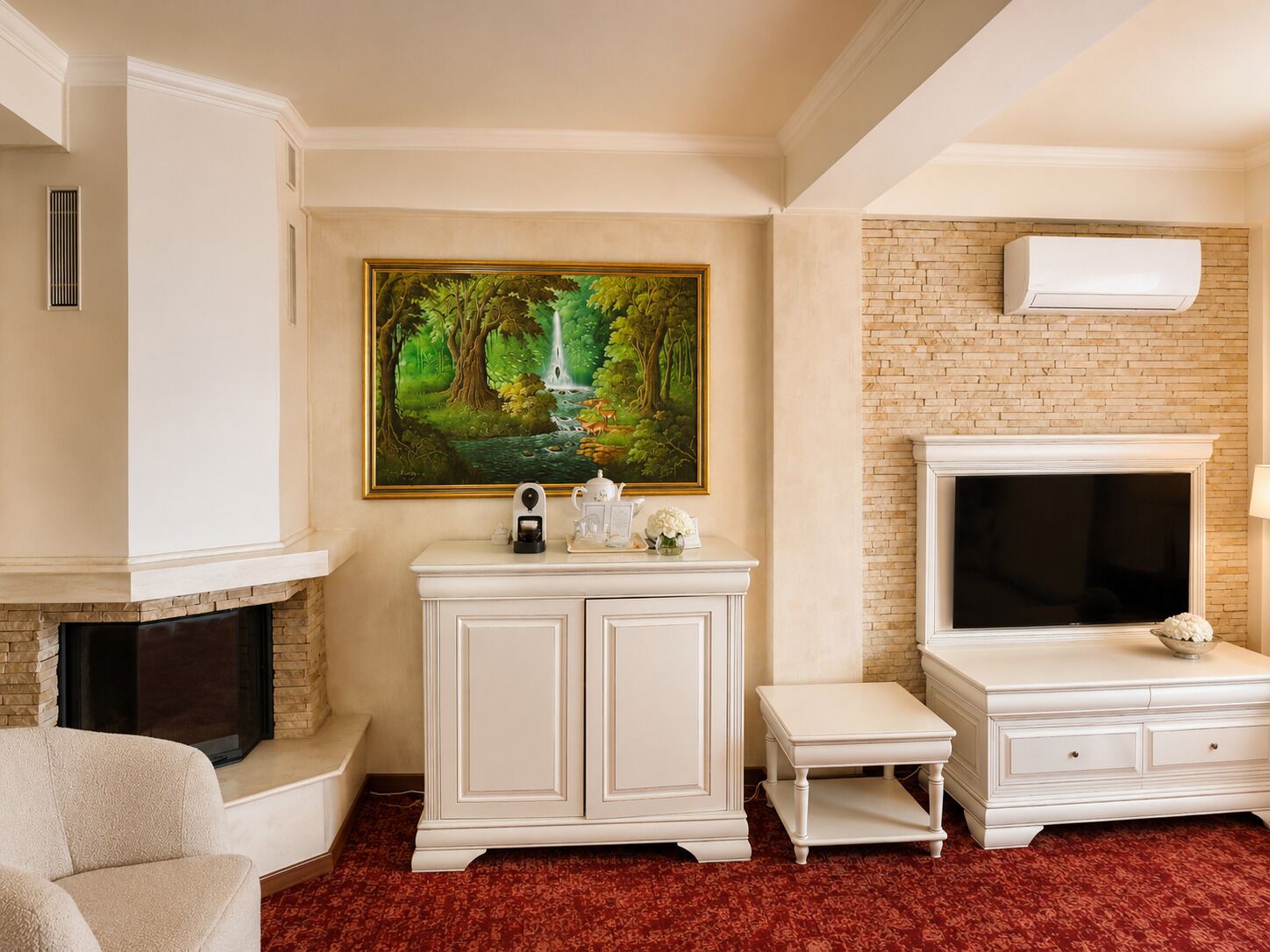 Una sala de estar con chimenea, un armario blanco, un televisor y un cuadro de una escena forestal.