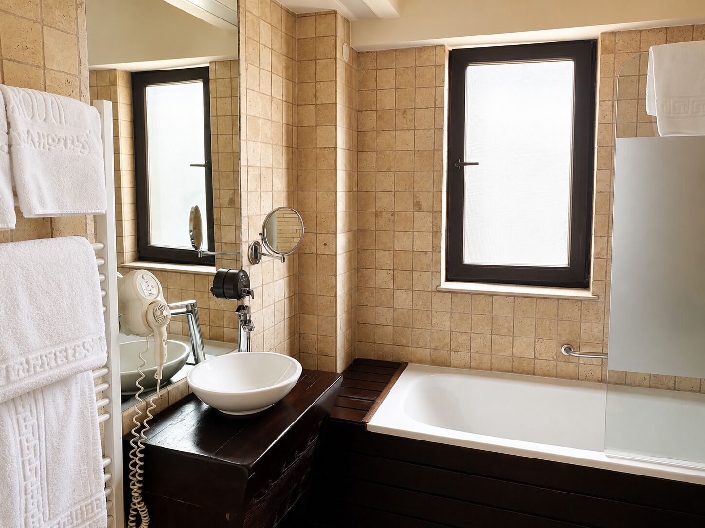 A bathroom with a bathtub, a sink, a mirror, and a window.