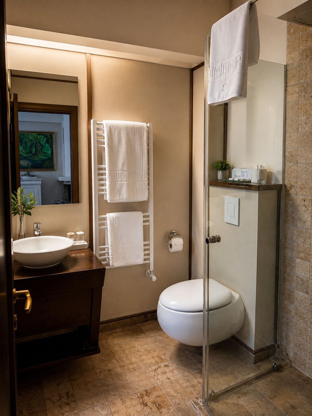 A bathroom with a sink, toilet, and shower. There are towels hanging on a rack, a mirror, and a framed picture on the wall.