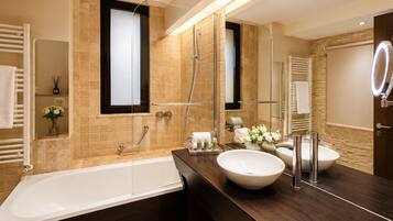 A modern bathroom with a bathtub, two sinks, a large mirror, and a shower.