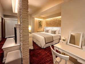 A hotel room with a bed, a desk, a chair, a dresser, and a mirror.