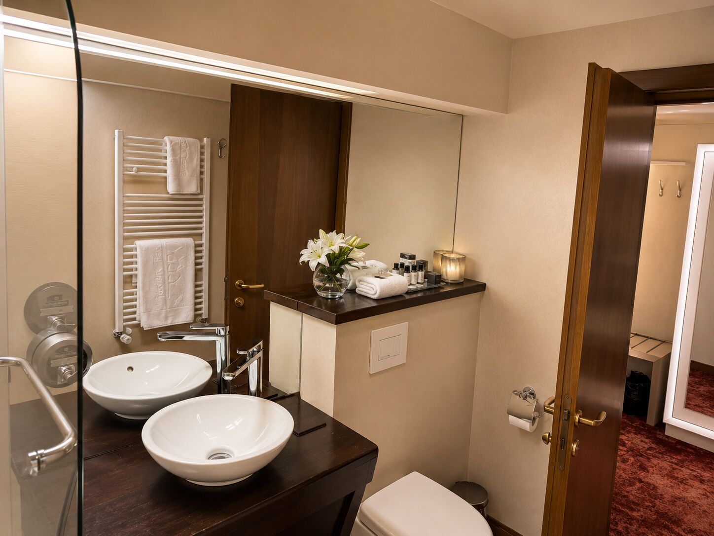 A bathroom with two sinks, a mirror, a towel rack, and a toilet.