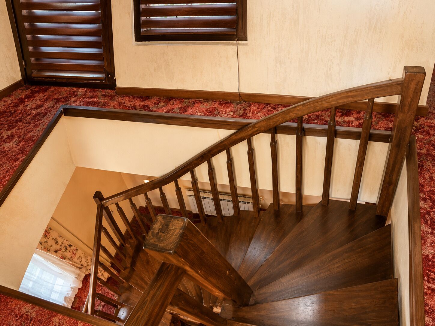 A wooden staircase with a handrail, carpeted steps, and a window with blinds.