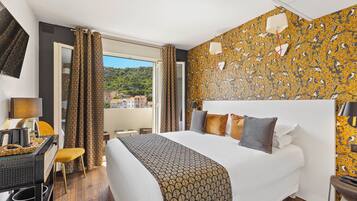 A hotel room with a bed, a desk, a chair, and a view of the city.