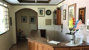 Een receptie met een houten balie, foto's in lijsten aan de muur en een betegelde vloer.