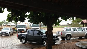 Een parkeerplaats met verschillende voertuigen, waaronder een zwarte pick-up truck en een witte bus.