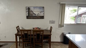 A dining area with a table and chairs, a painting on the wall, and a 'No Smoking' sign.