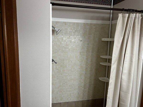 A shower with mosaic tiles and a white curtain.