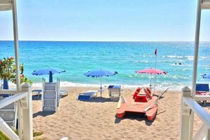 A beach with umbrellas, lounge chairs, and a lifeguard stand.